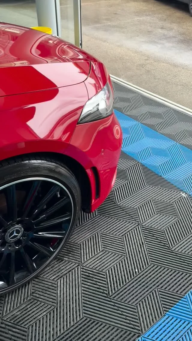 Roter Kompaktwagen auf dem gerasterten Hallenboden mit blauen Streifen